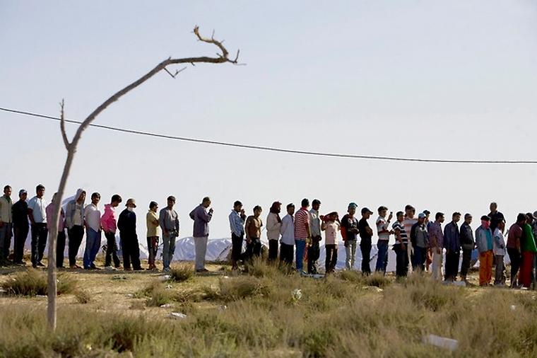 Muži čekající na jídlo v uprchlickém táboře na hranicích Libye a Tuniska.