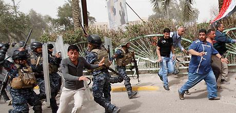 Riot policemen disperse protesters during a demonstration in Basra